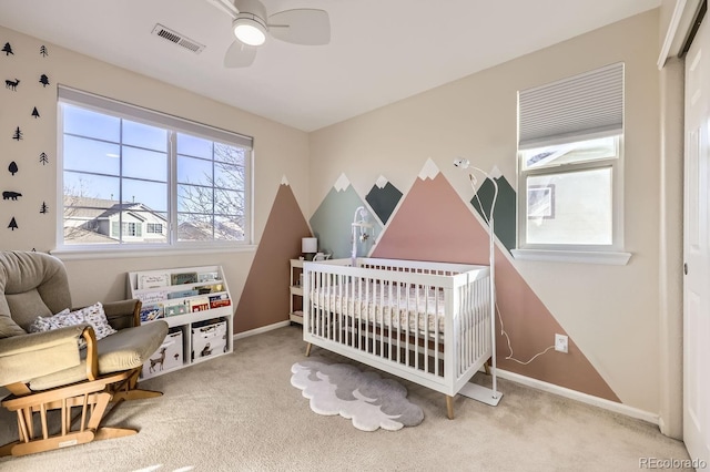 carpeted bedroom with ceiling fan, a closet, and a crib