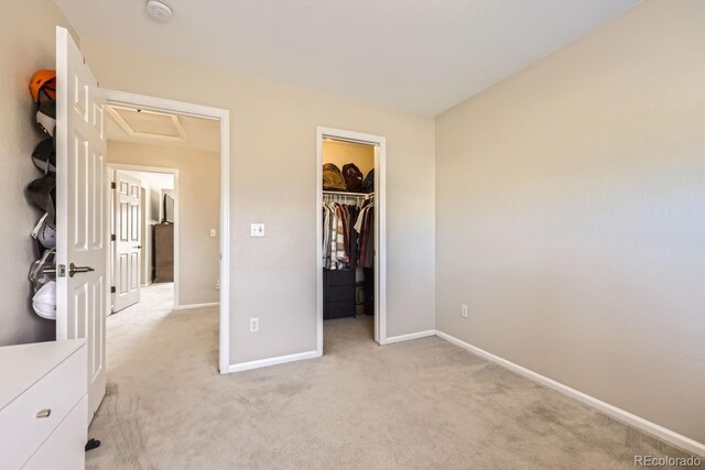 unfurnished bedroom featuring light carpet, a closet, and a spacious closet