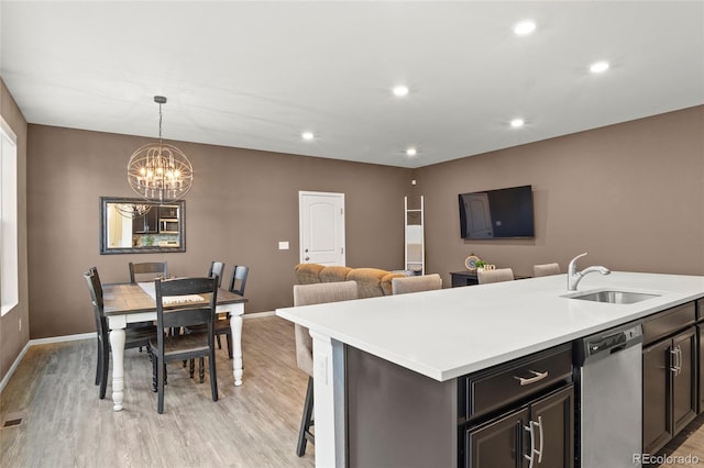 kitchen featuring light countertops, stainless steel dishwasher, a sink, and light wood-style flooring