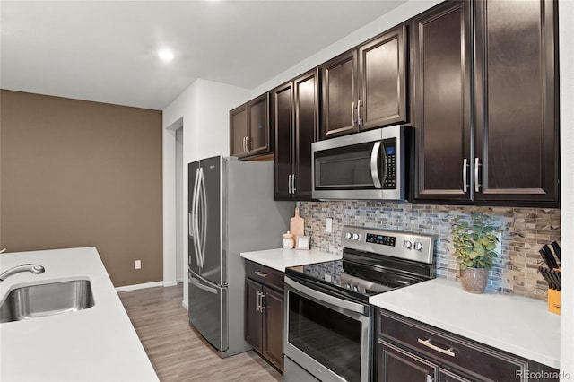 kitchen with a sink, light countertops, appliances with stainless steel finishes, dark brown cabinets, and decorative backsplash