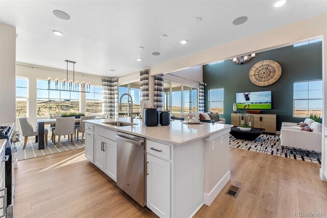 kitchen featuring sink, white cabinetry, hanging light fixtures, appliances with stainless steel finishes, and a kitchen island with sink