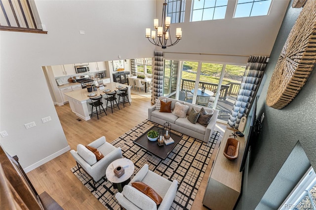 living room with a high ceiling, light hardwood / wood-style flooring, and a notable chandelier