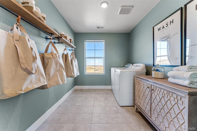 laundry area with light tile patterned flooring, a textured ceiling, and independent washer and dryer