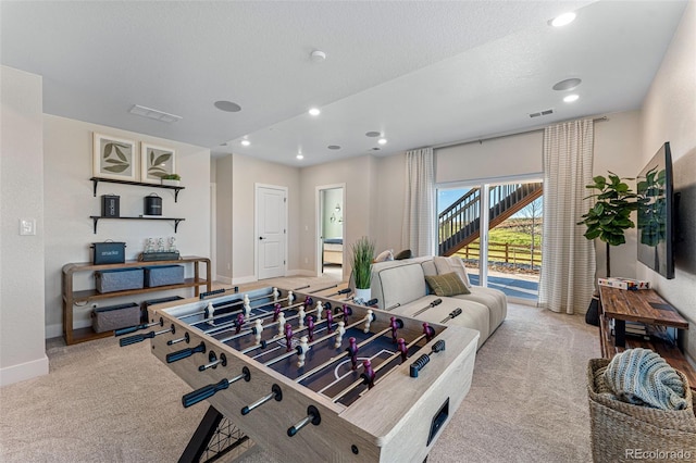 recreation room with light colored carpet and a textured ceiling