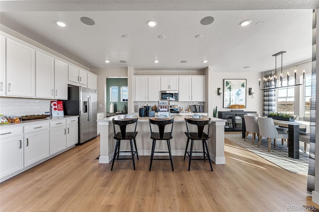 kitchen featuring white cabinetry, stainless steel appliances, and a center island with sink