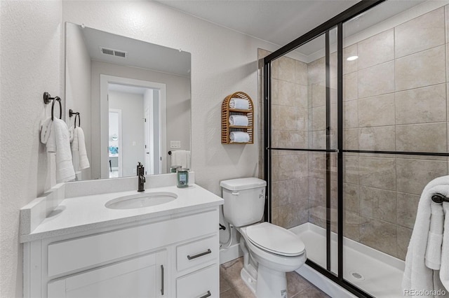 bathroom featuring tile patterned flooring, vanity, toilet, and walk in shower