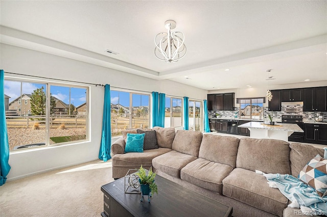 living area featuring visible vents, light colored carpet, a notable chandelier, and a healthy amount of sunlight