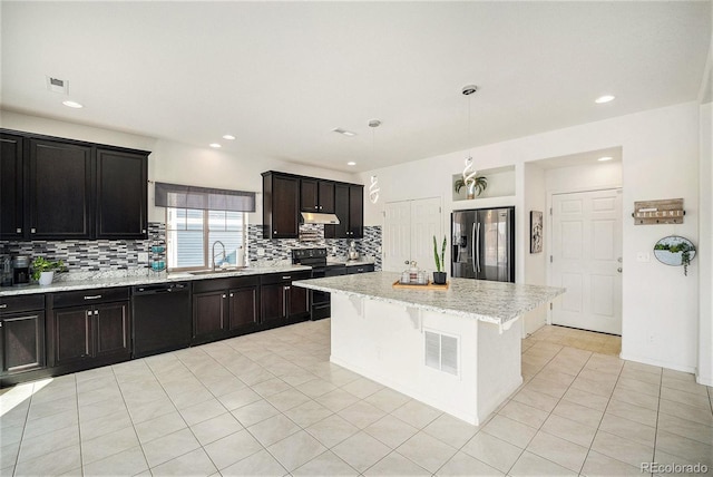 kitchen featuring tasteful backsplash, visible vents, a sink, under cabinet range hood, and black appliances
