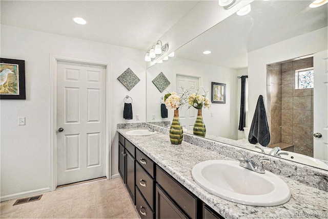full bath featuring baseboards, double vanity, a sink, and visible vents
