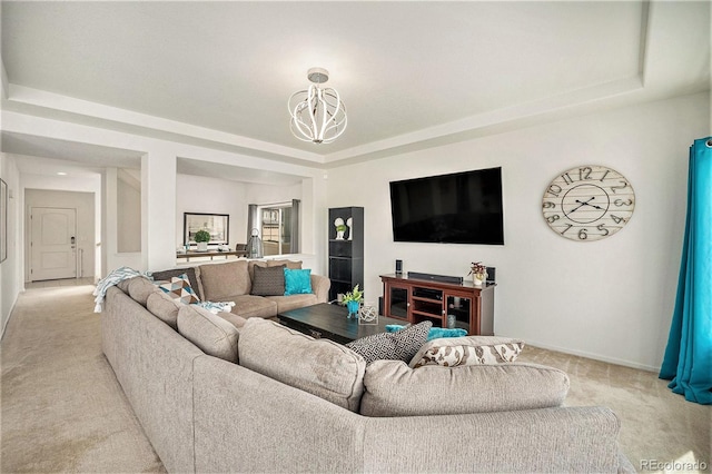 living area with light carpet, baseboards, a chandelier, and a raised ceiling
