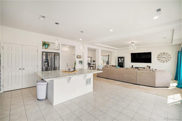 kitchen with a kitchen island, light tile patterned floors, visible vents, and stainless steel fridge