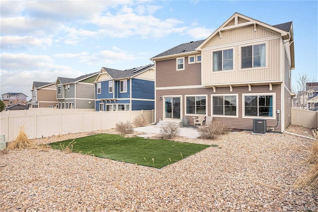 back of property featuring a residential view, a patio area, central AC unit, a fenced backyard, and a lawn