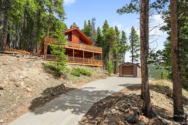 489 Harris Dr, Idaho Springs, CO 80452 - view of front of home featuring an outbuilding, a chimney, a deck, concrete driveway, and a detached garage