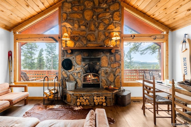 489 Harris Dr, Idaho Springs, CO 80452 - living area with wooden ceiling, vaulted ceiling, wood-type flooring, a stone fireplace, and baseboards