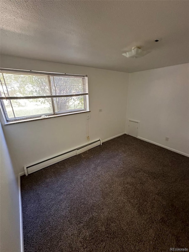 empty room with a baseboard heating unit, dark carpet, and a textured ceiling