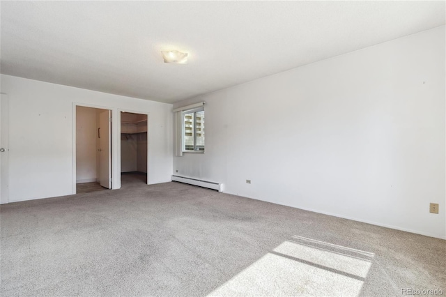 unfurnished bedroom with baseboard heating, a walk in closet, carpet floors, and a closet