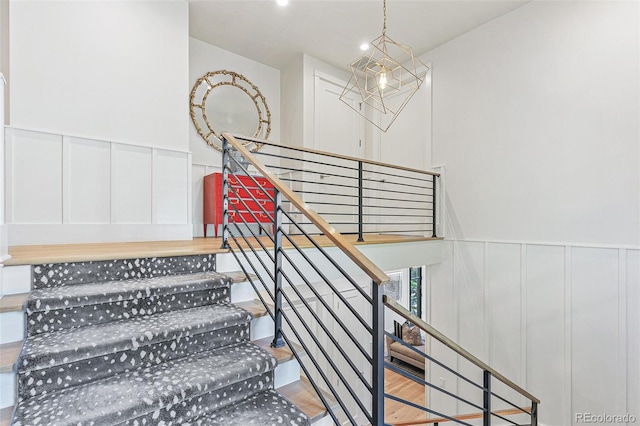 stairway featuring hardwood / wood-style floors and a notable chandelier