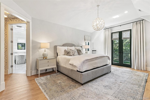 bedroom featuring light hardwood / wood-style flooring, a notable chandelier, access to exterior, and french doors