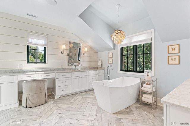 bathroom with vanity, lofted ceiling, plenty of natural light, and a washtub