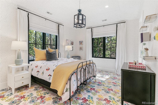 bedroom featuring multiple windows, a textured ceiling, and a chandelier