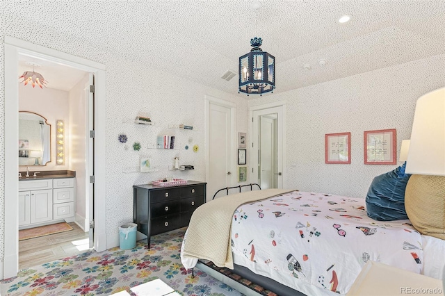 bedroom with sink, light hardwood / wood-style flooring, and ensuite bathroom