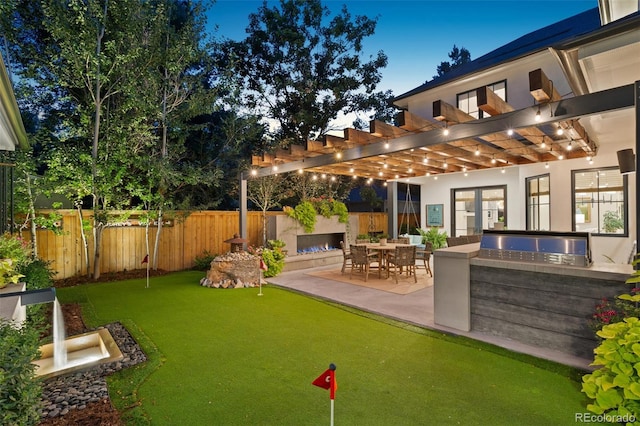 yard at dusk with area for grilling, exterior bar, a pergola, and a patio area