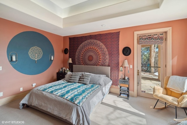 carpeted bedroom with access to exterior and a tray ceiling