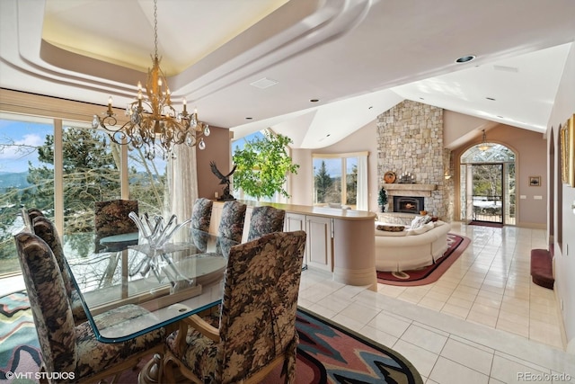 dining area featuring light tile patterned floors, a fireplace, a wealth of natural light, and an inviting chandelier