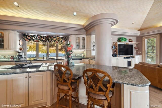 kitchen with light hardwood / wood-style floors, sink, dark stone counters, and vaulted ceiling