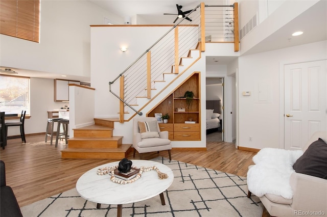 living room featuring a high ceiling, light hardwood / wood-style flooring, and ceiling fan