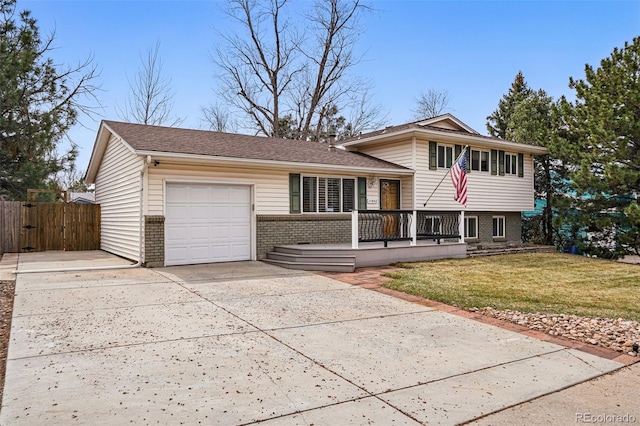 tri-level home with fence, a front yard, brick siding, concrete driveway, and an attached garage
