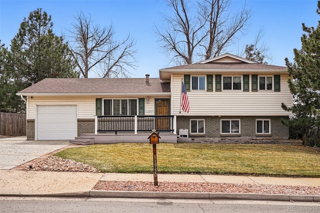 split level home with a porch, driveway, a front yard, brick siding, and an attached garage