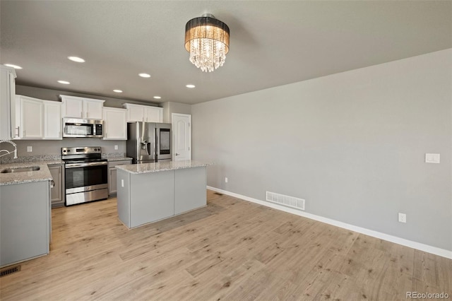 6154 Fiddle Way, Colorado Springs, CO 80925 - kitchen with appliances with stainless steel finishes, a kitchen island, recessed lighting, light wood finished floors, and a chandelier