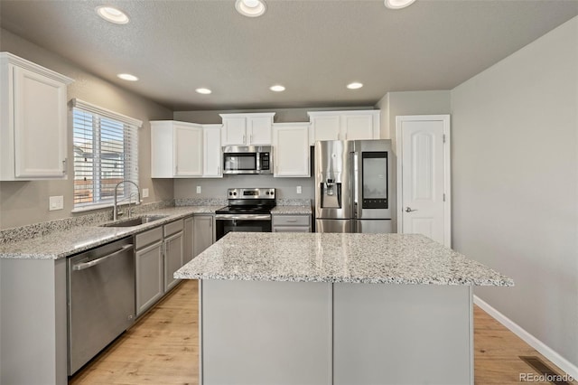 6154 Fiddle Way, Colorado Springs, CO 80925 - kitchen featuring stainless steel appliances, a kitchen island, light wood-style floors, light stone countertops, and white cabinetry