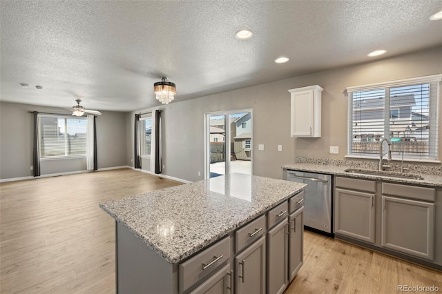 6154 Fiddle Way, Colorado Springs, CO 80925 - kitchen with stainless steel dishwasher, gray cabinetry, a textured ceiling, a center island, and light wood-style floors