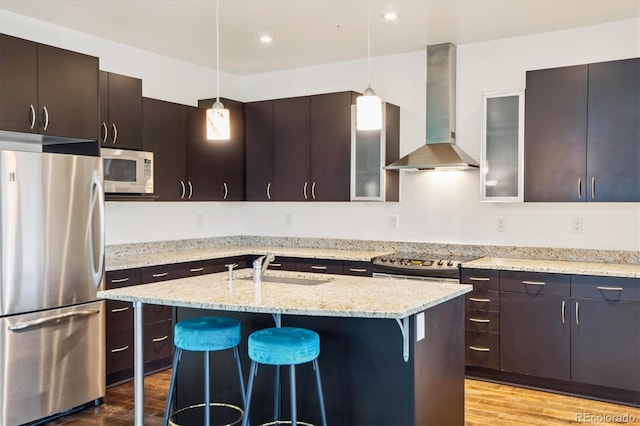 2958 Syracuse St Unit 317, Denver, CO 80238 - kitchen with stainless steel appliances, wall chimney exhaust hood, a kitchen bar, a sink, and light wood-type flooring