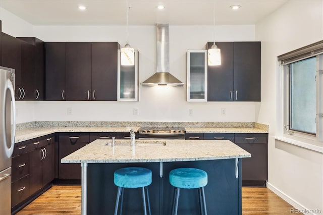 2958 Syracuse St Unit 317, Denver, CO 80238 - kitchen with wall chimney exhaust hood, stainless steel appliances, light wood-style floors, a sink, and decorative light fixtures