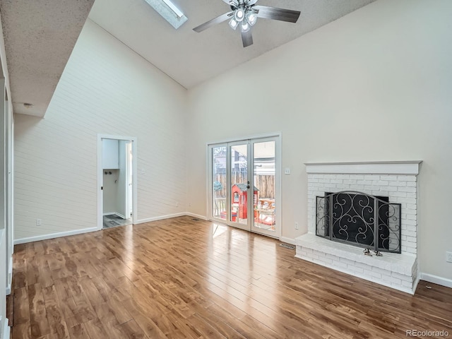 unfurnished living room with a brick fireplace, high vaulted ceiling, hardwood / wood-style floors, and ceiling fan