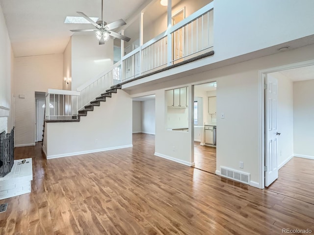 unfurnished living room featuring hardwood / wood-style flooring, ceiling fan, and a high ceiling