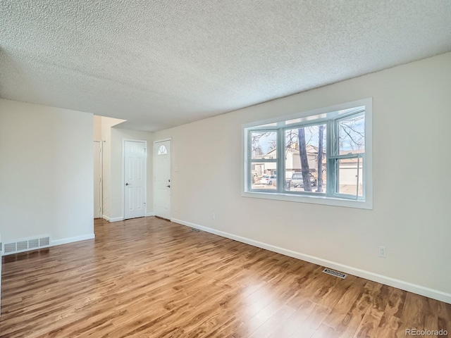 unfurnished room with a textured ceiling and light hardwood / wood-style flooring