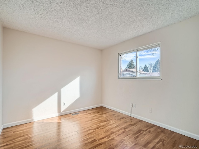 unfurnished room with hardwood / wood-style floors and a textured ceiling