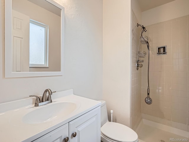 bathroom with vanity, a tile shower, and toilet