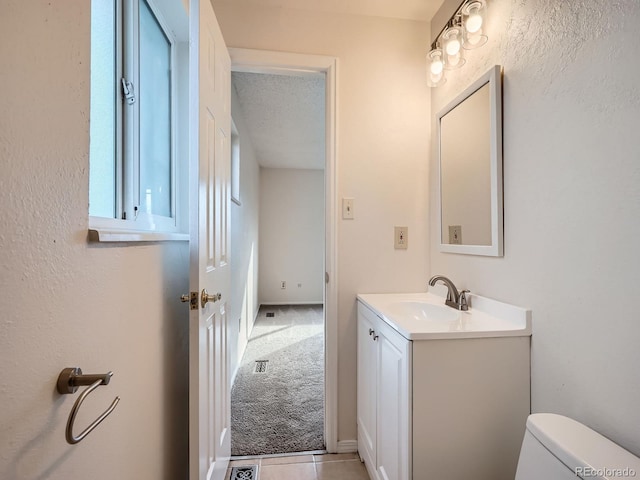 bathroom featuring vanity, a textured ceiling, tile patterned floors, and toilet