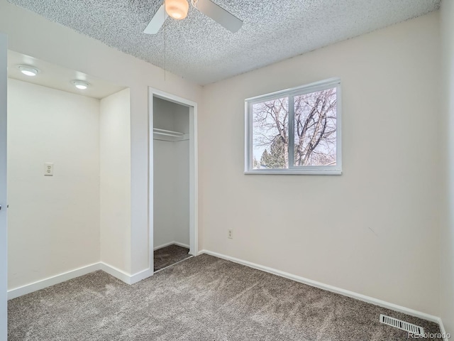 unfurnished bedroom featuring ceiling fan, a closet, a textured ceiling, and carpet