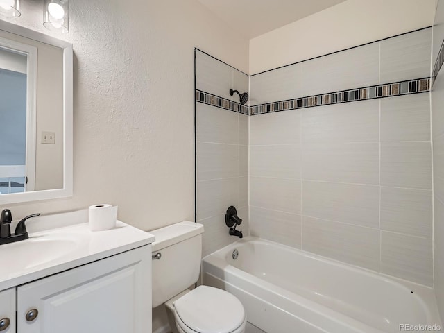 full bathroom featuring tiled shower / bath combo, vanity, and toilet