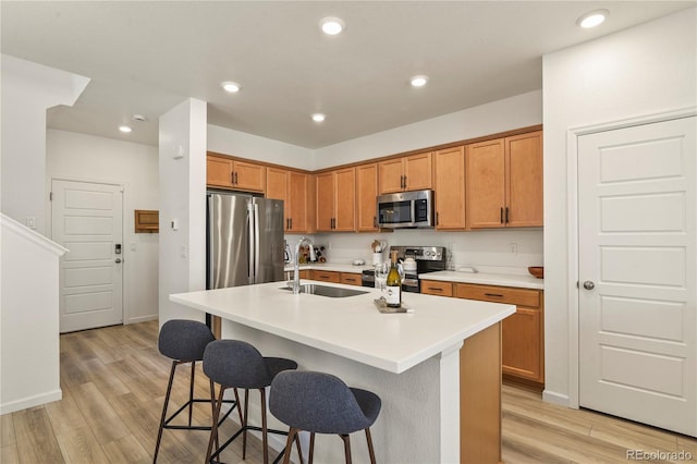 23920 E 34th Ave, Aurora, CO 80019 - kitchen with appliances with stainless steel finishes, a sink, a kitchen breakfast bar, light wood-style flooring, and recessed lighting