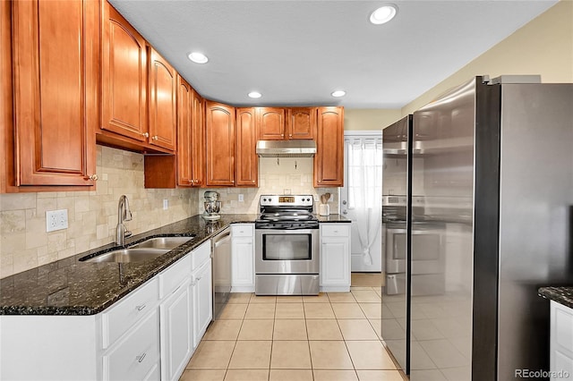 kitchen with appliances with stainless steel finishes, a sink, dark stone countertops, backsplash, and under cabinet range hood