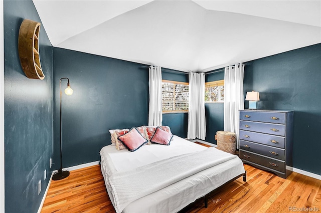bedroom with baseboards, wood finished floors, and lofted ceiling