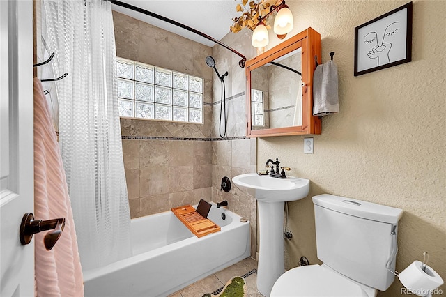 full bath featuring tile patterned floors, a textured wall, shower / bath combo, and toilet