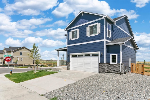 view of front facade featuring fence, an attached garage, concrete driveway, and stone siding
